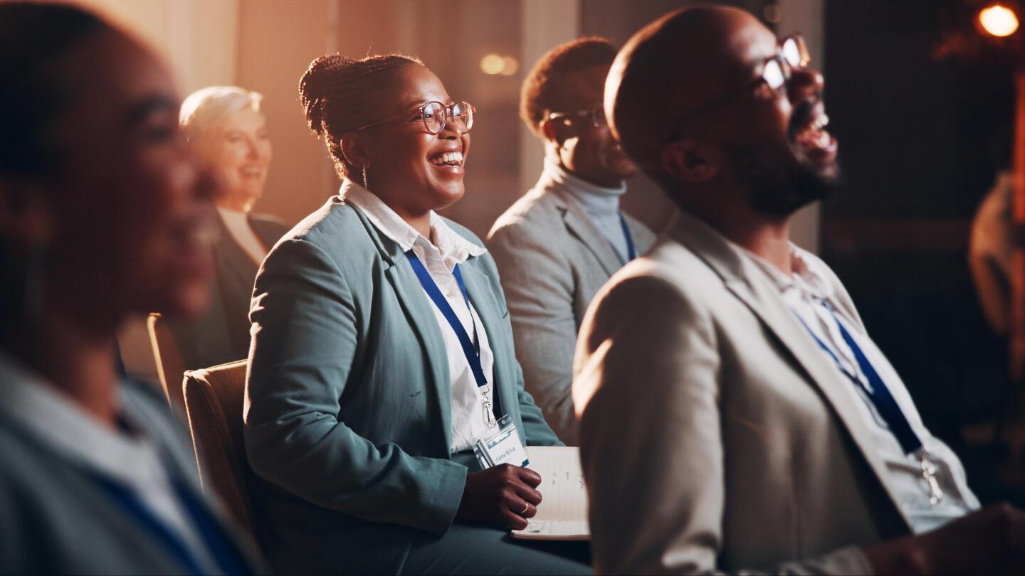 Smiling participants in an accessible conference hall, attentively engaged during an event.