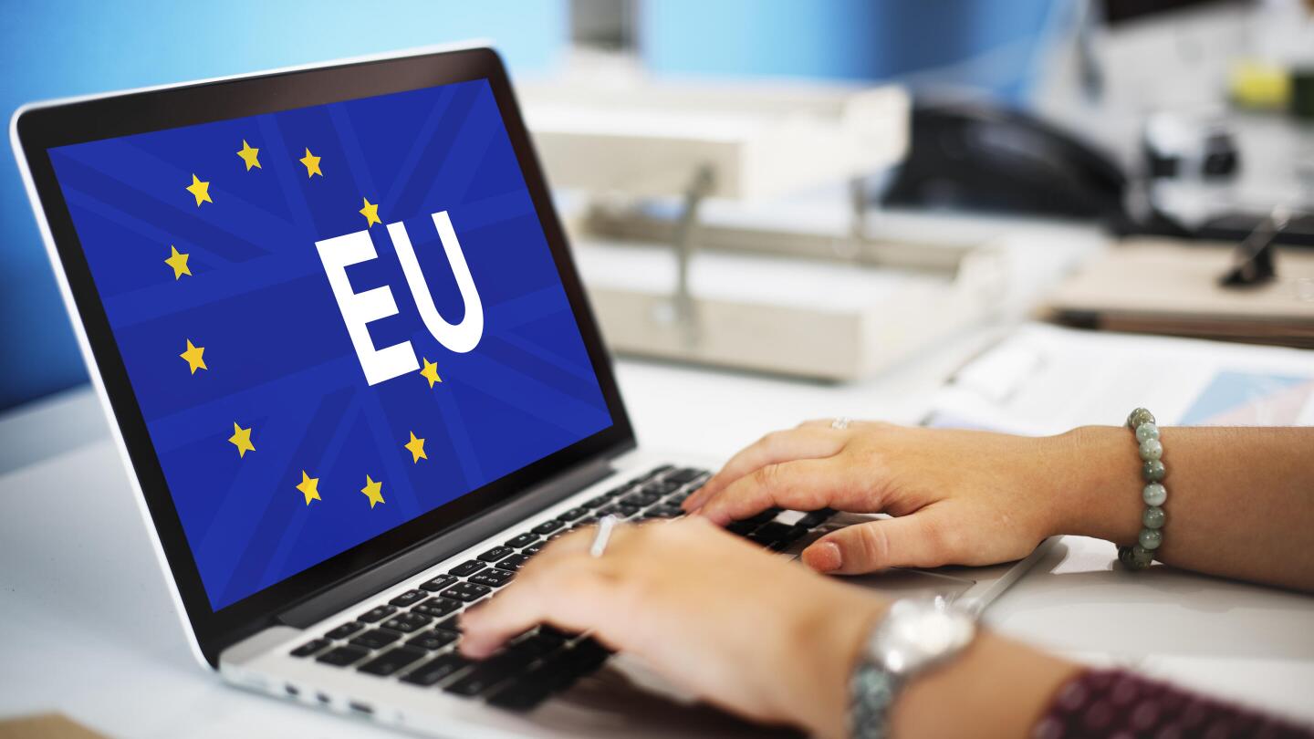 Hands typing on a laptop displaying the EU flag – a symbol of the new Accessibility Directive.