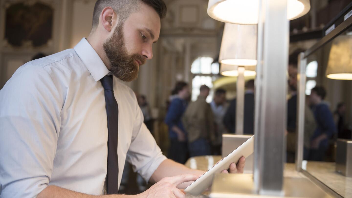 Business-Mann am Tisch mit Tablet in der Hand, Menschen im Hintergrund